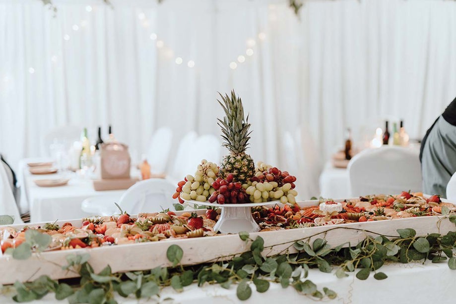 Long grazing board on table with elevated area showcasing grapes and a pineapple